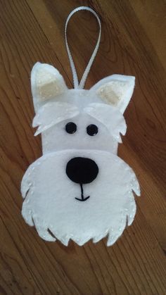 a white dog ornament hanging from a wooden table with a string attached to it