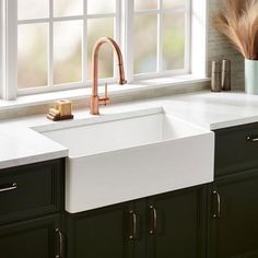 a white kitchen sink sitting under a window next to a counter top with brown cabinets