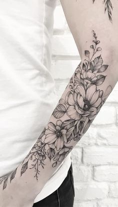 a woman's arm with flowers and leaves on it