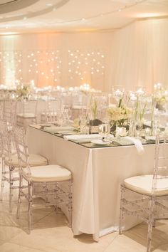 the tables are set up with white linens and centerpieces for an elegant wedding reception