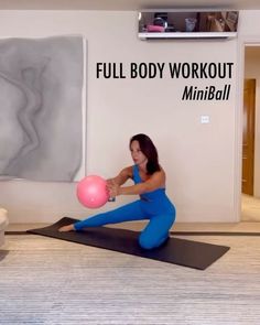 a woman is sitting on a yoga mat and holding a pink ball