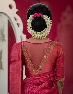 the back of a woman's head with flowers in her hair, wearing a pink saree