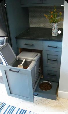 a kitchen with a dog bowl in the middle of it and a trash can next to it