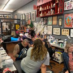 a group of people sitting in a room with lots of artwork on the wall behind them