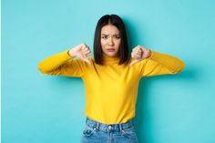 a woman in a yellow shirt is posing with her fist up and looking at the camera