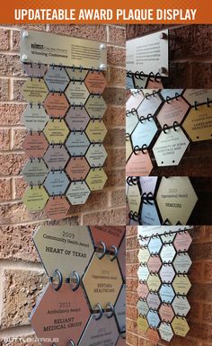 the award plaque display is hanging up against a brick wall with several different plaques attached to it