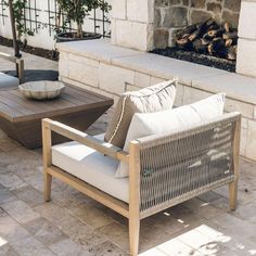 two chairs and a table sitting on a patio with an outdoor fireplace in the background