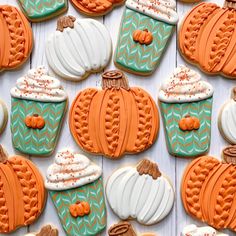 many decorated pumpkins and cupcakes on a white wooden table with blue and orange icing