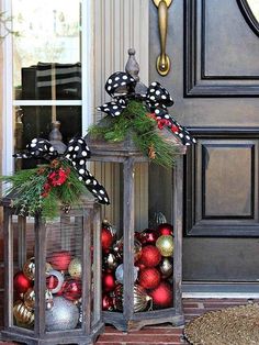 two lanterns decorated with christmas ornaments on the front porch