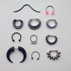 there are many different types of piercings on this white surface, including nose rings