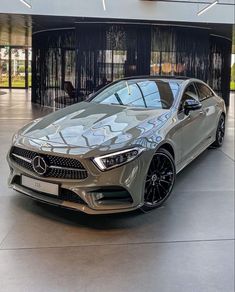 the mercedes cla is parked in front of a large building with black curtains on it