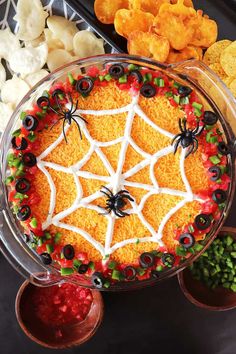 a spider web cake is decorated with candy and sprinkles, surrounded by other snacks