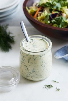 a glass jar filled with dressing next to a salad