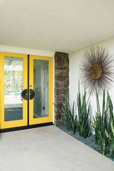 a yellow door is in front of a brick wall with cactuses on the side