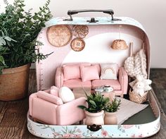 an open suitcase sitting on top of a wooden table next to a potted plant