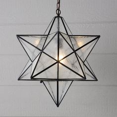 a moravian star hanging from the ceiling with light bulbs on it's sides and two lights in the middle