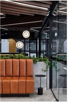 an office with brown leather couches and plants in the corner, next to glass walls