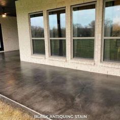 a concrete patio with three windows and grass in the foreground, on a sunny day