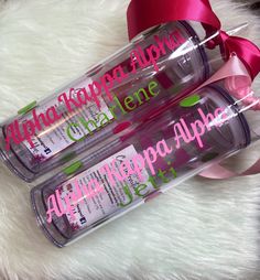 two personalized water bottles with pink and green lettering on them, one is empty