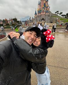 a man and woman hugging each other in front of a castle