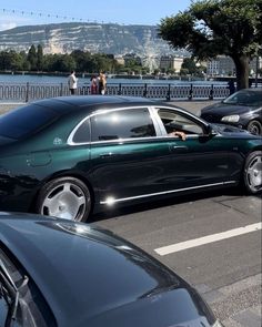 there is a car that is parked in the street next to other cars and people