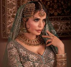 a beautiful woman in a green and gold bridal outfit with jewelry on her head