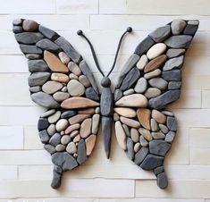 a butterfly made out of rocks sitting on top of a wall