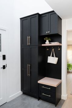 an entryway with black cabinets and white bags on the shelf, next to a door