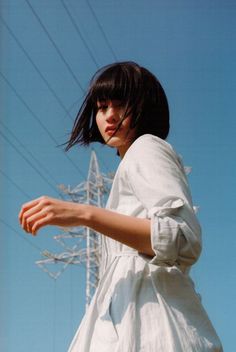 a woman standing in front of power lines with her hand out to the side,