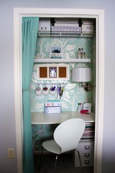 a white chair sitting in front of a desk under a blue curtain with pictures on it