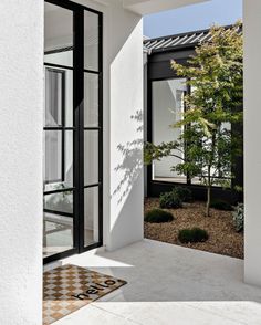 an open door leading into a white house with black trim and glass doors on both sides