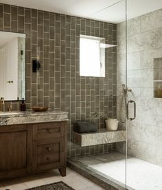 a bathroom with a walk in shower next to a sink and a mirror on the wall