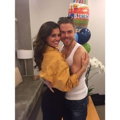 a man and woman hugging each other in front of a birthday cake