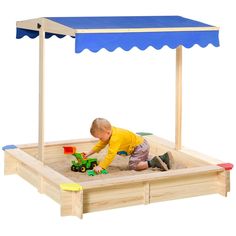 a young child playing in a sandbox with a blue awning over the top