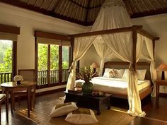 a bedroom with a canopy bed sitting on top of a hard wood floor next to windows