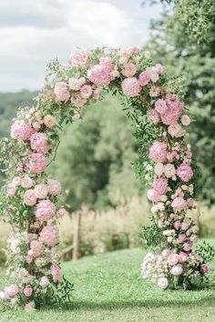 a pink flowered arch in the middle of a field