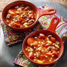 two red bowls filled with soup on top of a table