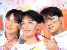 three young men with paint on their face and one wearing glasses, are posing for the camera