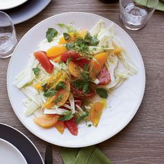 a white plate topped with lots of food on top of a table next to glasses and plates