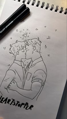 a drawing of two people kissing in front of a black marker pen on top of a piece of paper