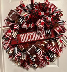 a red and black wreath with the word buccanell on it hanging from a door