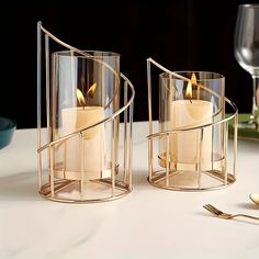 two candle holders with candles in them on a table