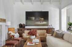 a living room filled with furniture and a large painting on the wall above it's fireplace