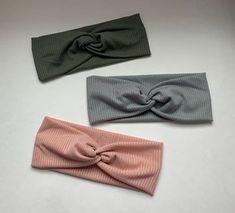 three different colored headbands on a white surface with one knoted in the middle