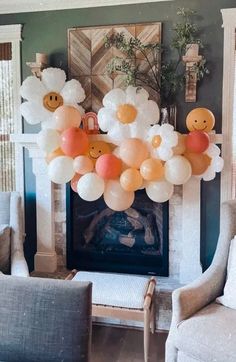 balloons in the shape of smiley faces are hanging from a fireplace mantel above two chairs