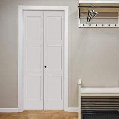 an empty room with two white doors and a bench in front of the closet door