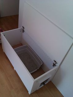 an open drawer on the floor in front of a wall with a dog bed inside