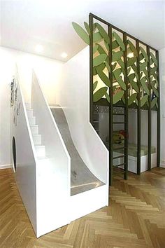 a staircase with a slide next to it in a room that has wood floors and white walls