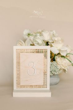 a vase with white flowers and a wooden table number