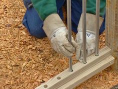 a person in blue pants and white gloves working on a piece of wood with metal bars